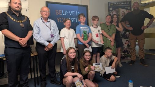 A group of people holding certificates and smiling, with some adults too.