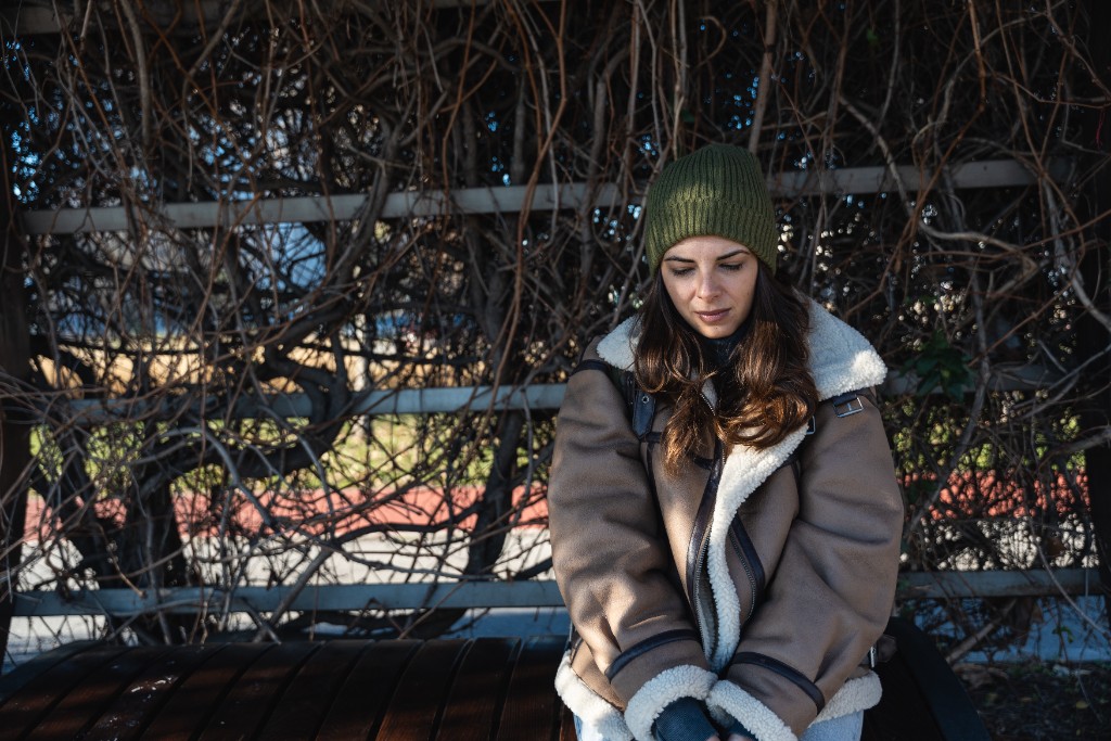 Girl sat alone outside in the cold wearing winter protective clothing