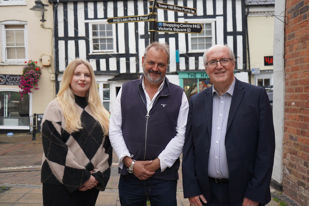 Three people stood in a line facing the camera in a Droitwich town centre street