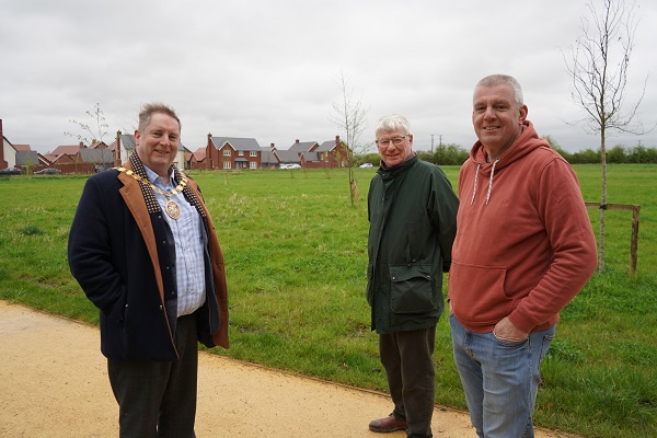 Three men stood on a path in front of a field
