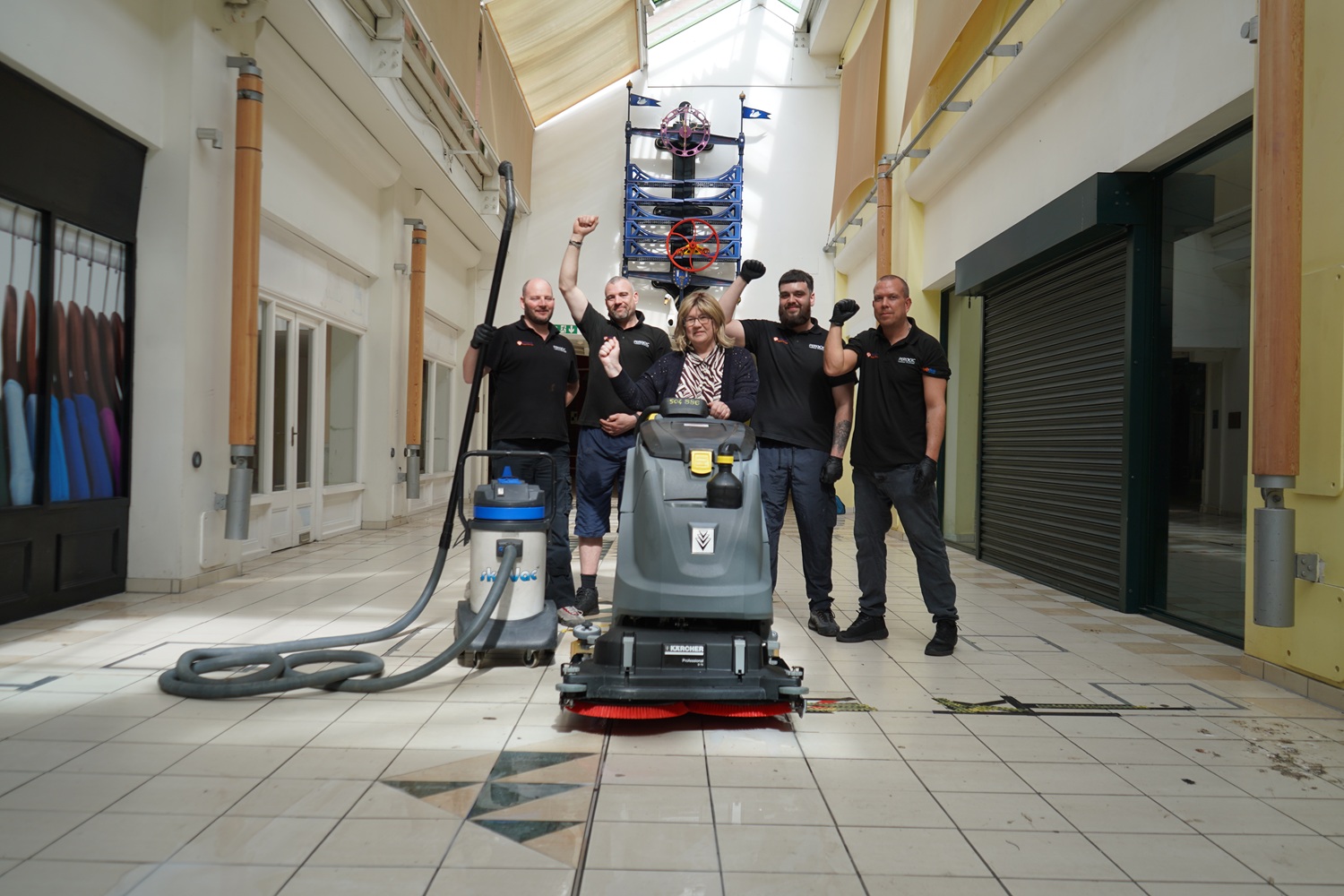 A group of people stood in a shopping centre in front of a pressure washer