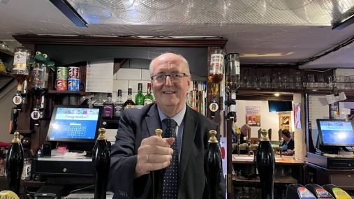 Cllr Morris behind a bar pulling a pint