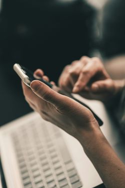 Person searching on their mobile device and using a laptop