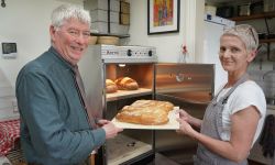 A man and a woman with a tray of bread