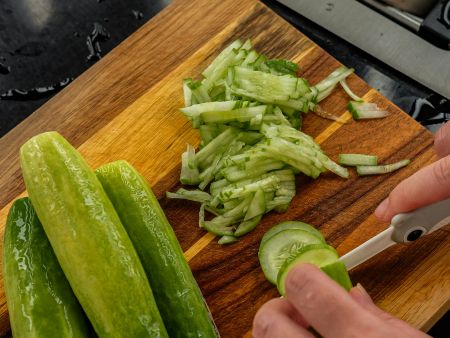 hands slicing cucumbers with a knife
