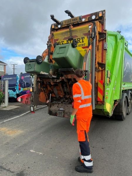 A collection worked loading a green recycling bin on to a lorry